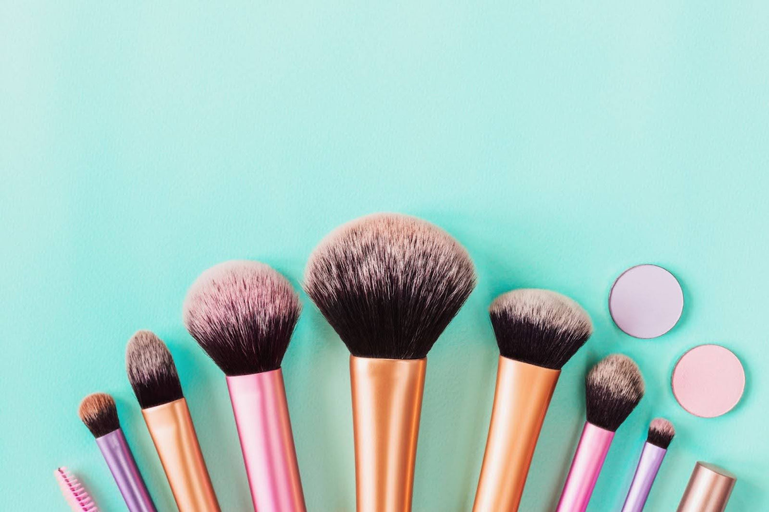 Makeup Brushes in a line on aqua colored background. 