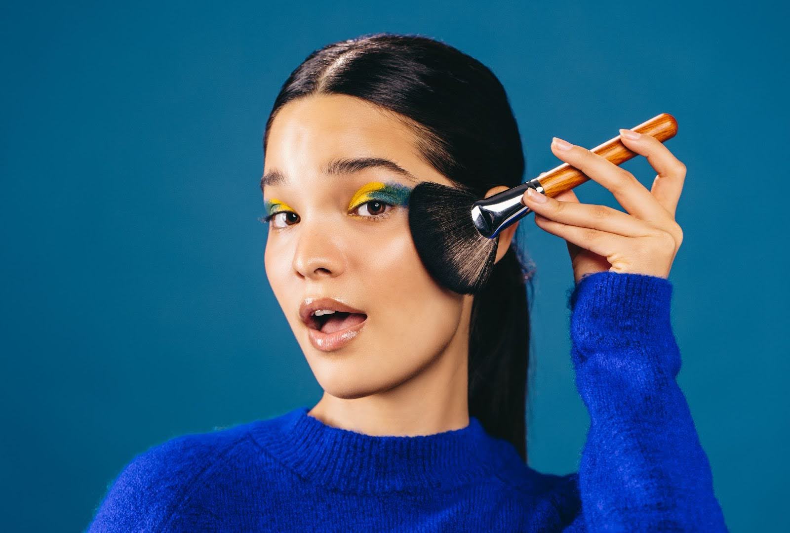 Girl showing how to apply makeup with a makeup brush.